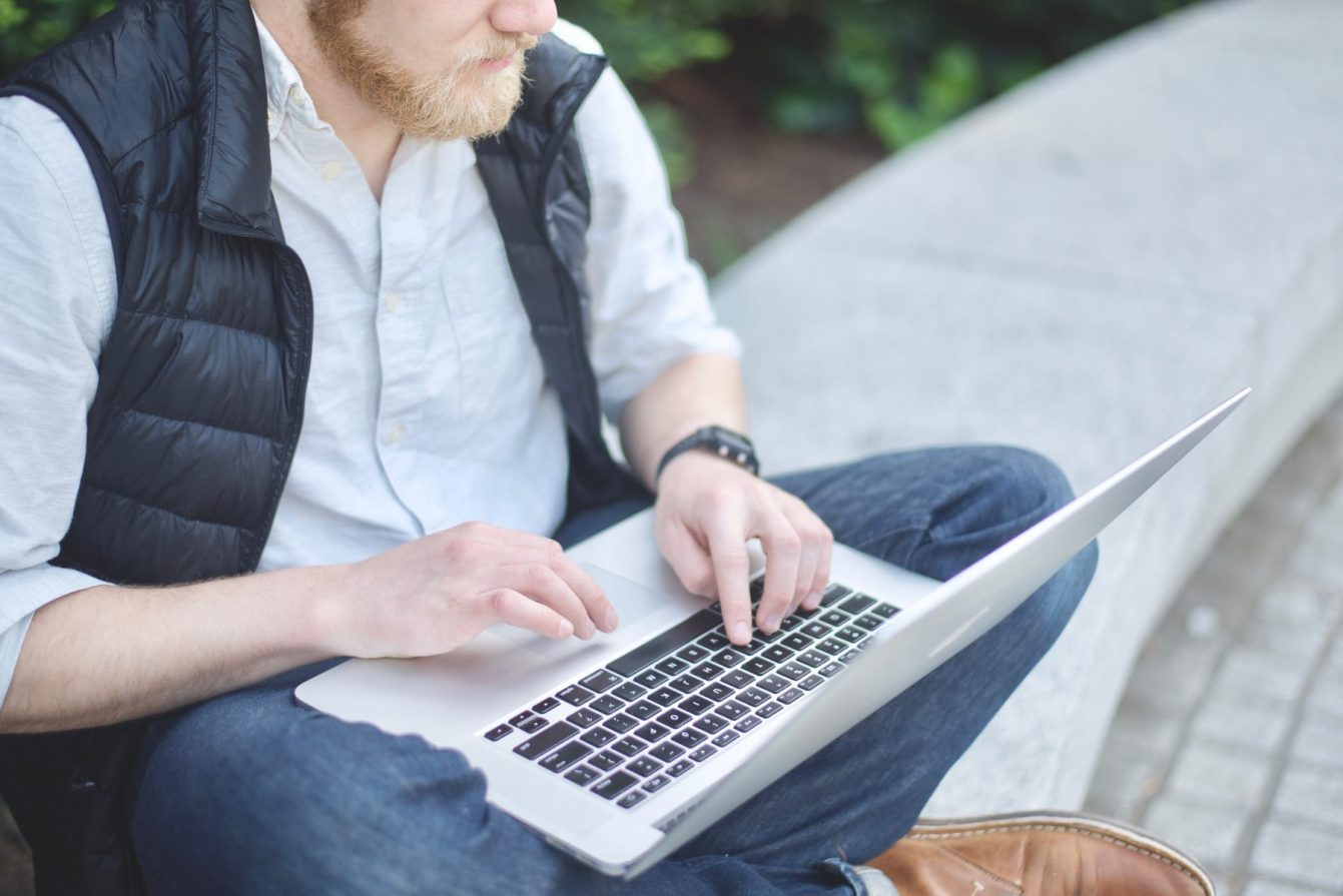Man sitting on granite bench working on laptop