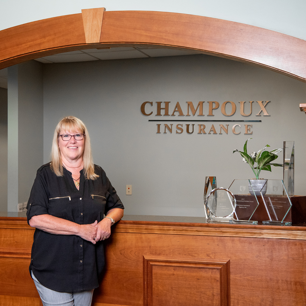 Photo of Diane Champoux Standing at the desk of Champoux Insurance.